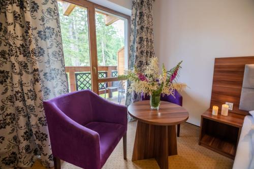 a room with a purple chair and a table and a window at Apart-Invest Nieruchomości Studio 30 in Szklarska Poręba