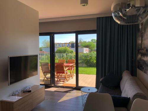 a living room with a couch and a television and a patio at Apartament Julian Seaside Gardenia in Dziwnów