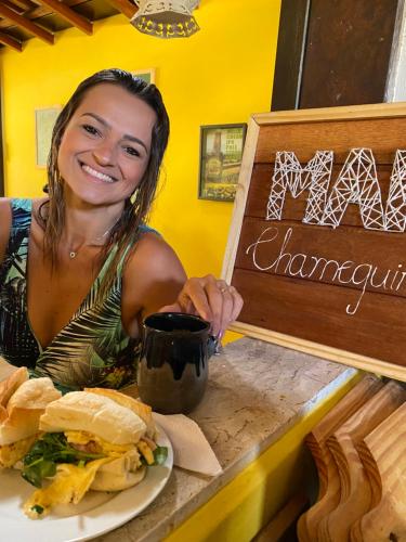 een vrouw die aan een tafel zit met een bord eten bij MAI Chameguin Hospedagens Paraty in Paraty