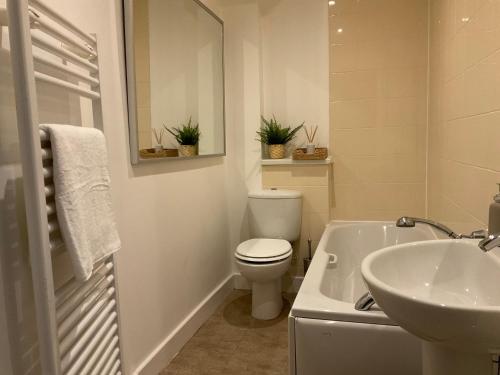 a white bathroom with a toilet and a sink at Modern 2 Bed Apt in Egham High Street, with private parking and Wifi in Egham