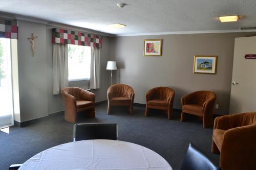 a waiting room with chairs and a table at Ermitage Saint-Antoine in Lac-Bouchette