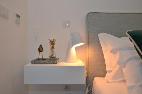 a lamp on a nightstand next to a bed at Oliva Teles 53 Apartments in Arcozelo