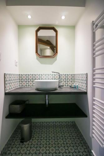 une salle de bain avec un lavabo et un miroir dans l'établissement Le Remarquable , appartement avec climatisation, à Sarlat-la-Canéda