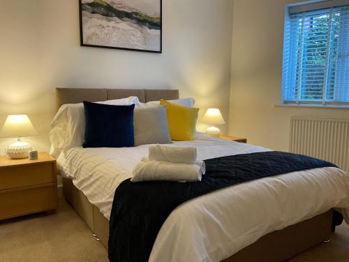 Modern 2 Bed Apt in Egham High Street, with private parking and Wifi في ايجهام: غرفة نوم بسرير كبير وبها وسائد زرقاء وصفراء