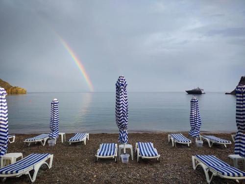 um grupo de cadeiras e guarda-sóis numa praia com arco-íris em Datca Masal Gibi Plaj&Restaurant em Datça