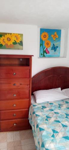 a bedroom with a bed and a dresser and a painting at Hostel Cidade Nova, próximo a estação metrô praça 11, onde você tem acesso direto a quaisquer Shows nas praias da zona Sul in Rio de Janeiro