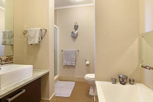 a bathroom with a white sink and a toilet at Penguin Haven . Luxury 2 bedroom, Boulders Beach. in Cape Town