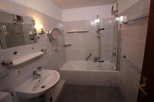 La salle de bains est pourvue d'une baignoire, d'un lavabo et d'une douche. dans l'établissement Parkside No 8, à Timmendorfer Strand