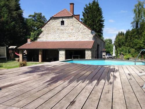 een buitenzwembad met een houten terras en een gebouw bij Gîte la casa del cookie in Chimay