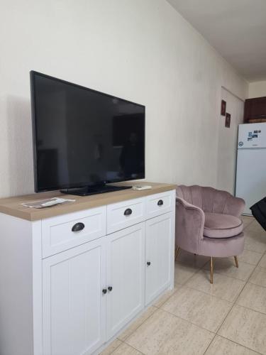 a living room with a large television and a chair at Nice apartment with amazing views in Kriopigi