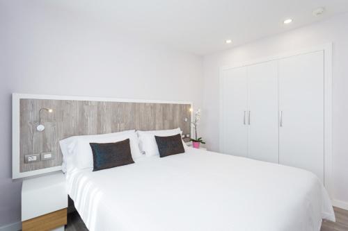 a white bedroom with a large white bed with pillows at Royal Sun Resort in Acantilado de los Gigantes