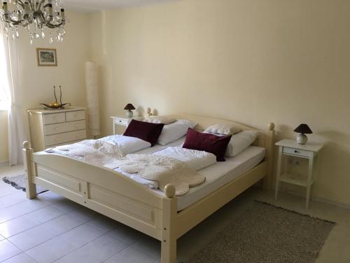 um quarto com uma cama branca e almofadas vermelhas em Villa Ida em Balatonmáriafürdő