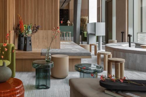 un vestíbulo con mesas, taburetes y jarrones en Buckle Street Studios by Locke, Aldgate, en Londres