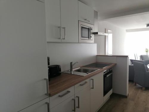 a kitchen with white cabinets and a sink and a stove at Ferienwohnungen Strandglück in Norddeich