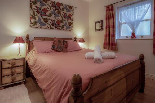 1 dormitorio con 1 cama grande con sábanas rosas y ventana en Arcadia - 1 Bedroom Apartment - Tenby en Tenby