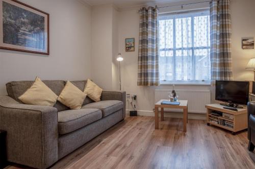 a living room with a couch and a tv at Arcadia - 1 Bedroom Apartment - Tenby in Tenby