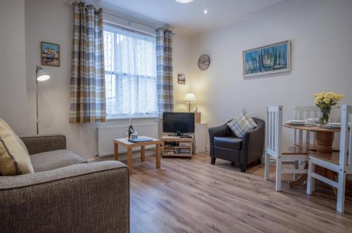 a living room with a couch and a tv and a table at Arcadia - 1 Bedroom Apartment - Tenby in Tenby