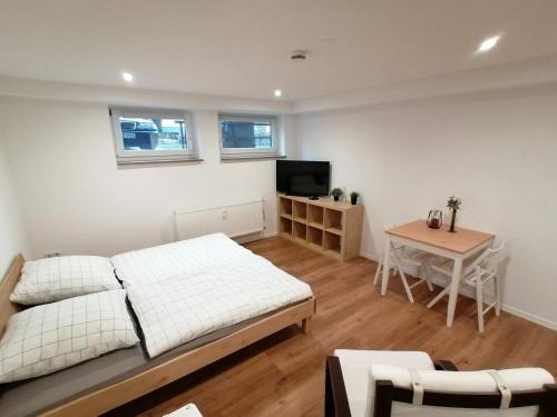 a bedroom with a bed and a table and a television at Filder-Apartment in Filderstadt