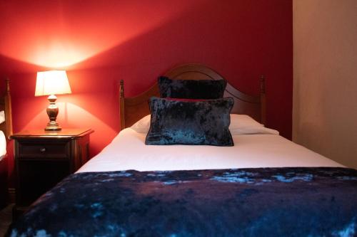 a red bedroom with a bed with a pillow on it at Bridge Hotel in Arklow