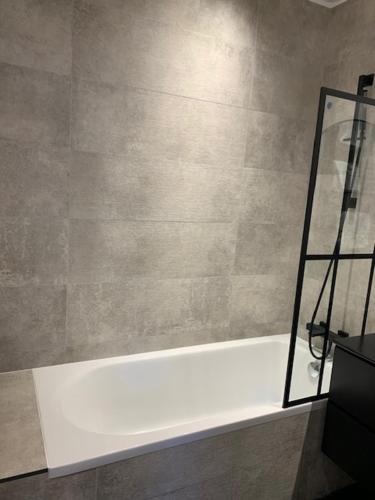 La salle de bains est pourvue d'une baignoire blanche. dans l'établissement Luxe Parisien - Petit Varenne, à Paris