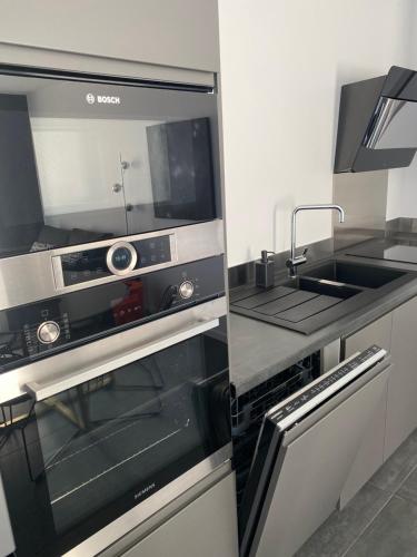 une cuisine avec une cuisinière et un évier dans l'établissement Logement Confort 2 Chambres / Séjour-cuisine proche de Montpellier, à Saint-Aunès