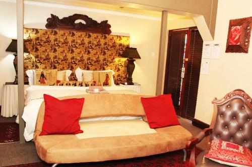 a bedroom with a bed and a couch with red pillows at Victoria Manor in Upington