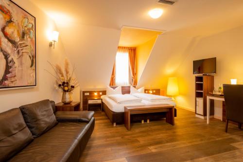 une chambre d'hôtel avec un lit et un canapé dans l'établissement BEHLs Genusshotel im Brennhaus, à Blankenbach