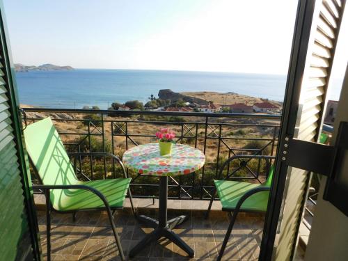 einen Tisch und Stühle auf einem Balkon mit Meerblick in der Unterkunft Studios Edem in Agios Ioannis Kaspaka