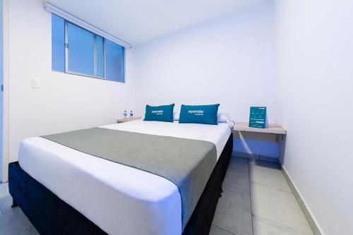 ein Schlafzimmer mit einem großen weißen Bett mit blauen Kissen in der Unterkunft Ayenda Panamericana in Manizales
