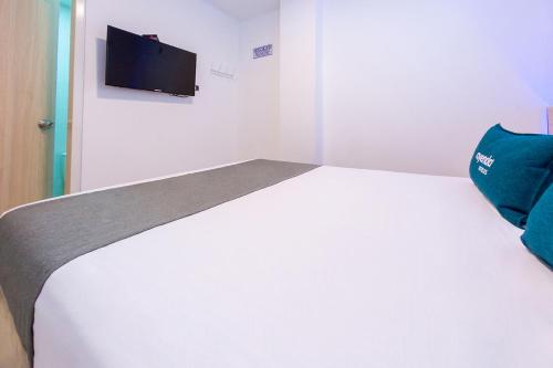 a bedroom with a white bed with a tv on the wall at Ayenda Panamericana in Manizales