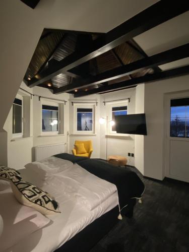 チュウフフにあるペンショナット プシェ ザムクのベッドルーム(大型ベッド1台、黄色い椅子付)