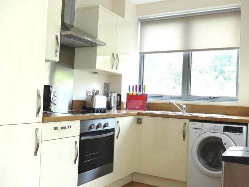 a kitchen with white cabinets and a washer and dryer at Basingstoke Apartments, Alencon Link Executive Serviced Apartments in Basingstoke