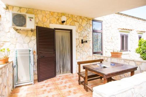 a patio with a wooden table and a stone wall at Tenuta Padre Pio in Vieste