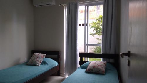 a bedroom with two twin beds and a window at Casas Adilio Florianopolis-norte in Florianópolis