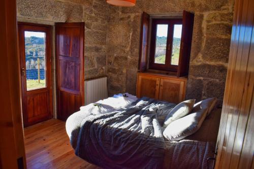 a bedroom with a bed in a stone wall at Casa Florestal, na Branda da Bouça dos Homens in Gavieira
