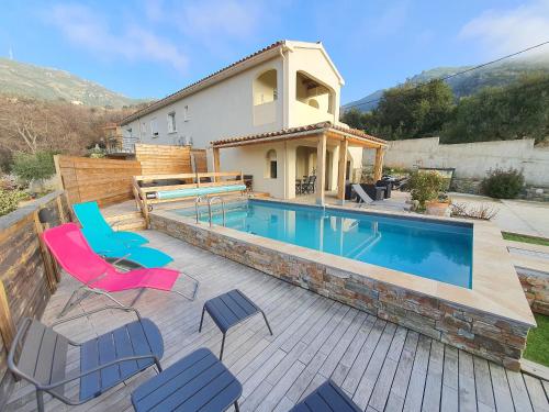 une piscine avec des chaises et une maison dans l'établissement Appartement Piovanacce - T3 avec pisicne privée 10min de Saint-Florent, à Barbaggio
