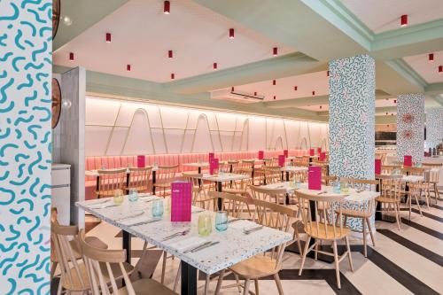 a dining room with tables and chairs and pink walls at Allegro Isora in Puerto de Santiago