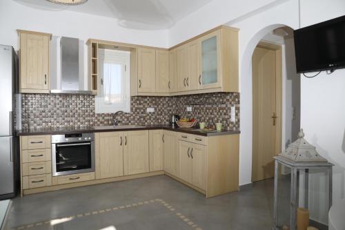 a kitchen with wooden cabinets and a stove top oven at Irida Vacation suites in Kastraki Naxou