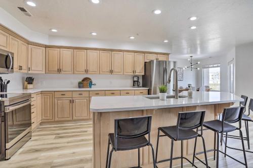 a kitchen with wooden cabinets and a large island with bar stools at Luxe Family Condo with Mtn View and Resort Perks! in St. George