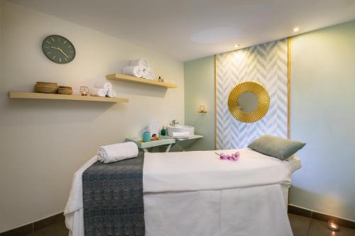 a spa room with a bed and a clock on the wall at Allegro Isora in Puerto de Santiago