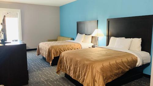 two beds in a hotel room with blue walls at Quality Inn & Suites in Edgefield
