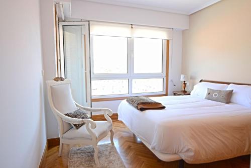 1 dormitorio con 1 cama, 1 silla y 1 ventana en Go Donosti Villa Berio, en San Sebastián