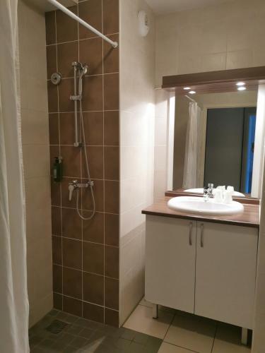 a bathroom with a sink and a shower with a mirror at Lagrange Aparthotel Toulouse Saint-Michel in Toulouse