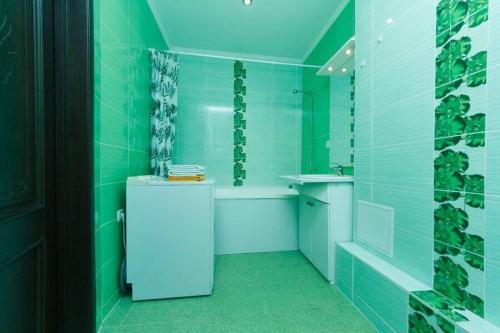 a green bathroom with a refrigerator and a bath tub at Светлая 3д in Kyiv