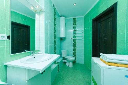 a green bathroom with a sink and a toilet at Светлая 3д in Kyiv