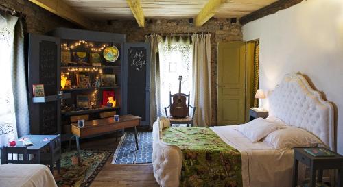 Ein Schlafzimmer mit einem Bett mit einer weißen Tagesdecke und ein Zimmer mit in der Unterkunft Maison d'Hôtes La Singulière in Sévérac-le-Château
