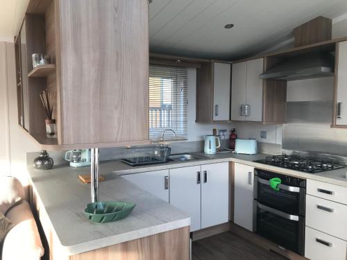 a kitchen with white cabinets and a stove top oven at Number 47 @ Lilliardsedge in Jedburgh