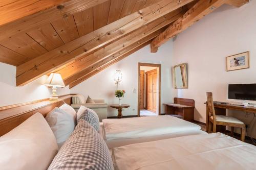 a bedroom with two beds and a desk at Hotel Blaue Gams ***S in Ettal