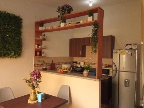 una cocina con nevera y una mesa con flores en La Casa Del Pinito, en Sonsonate