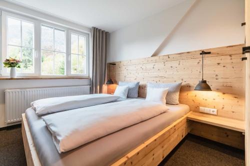 a bedroom with a large bed with a wooden wall at Hotel Blaue Gams ***S in Ettal
